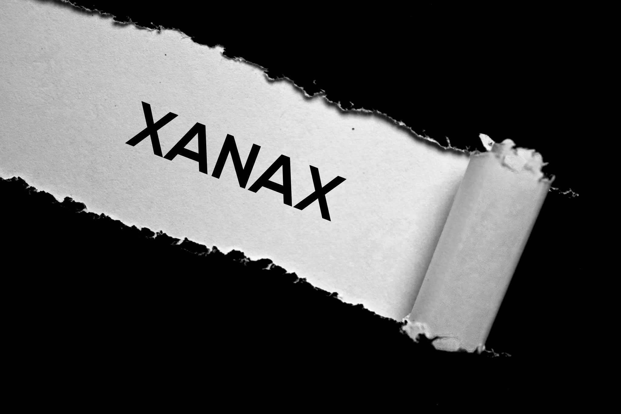 black paper torn away to reveal xanax and the risks of xanax addiction