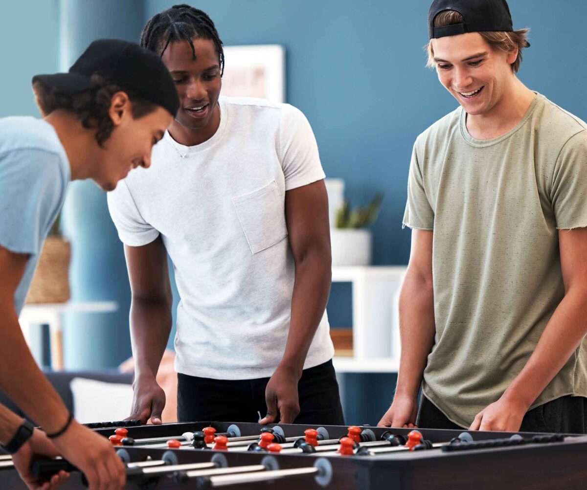 three young men playing foosball at inpatient rehab
