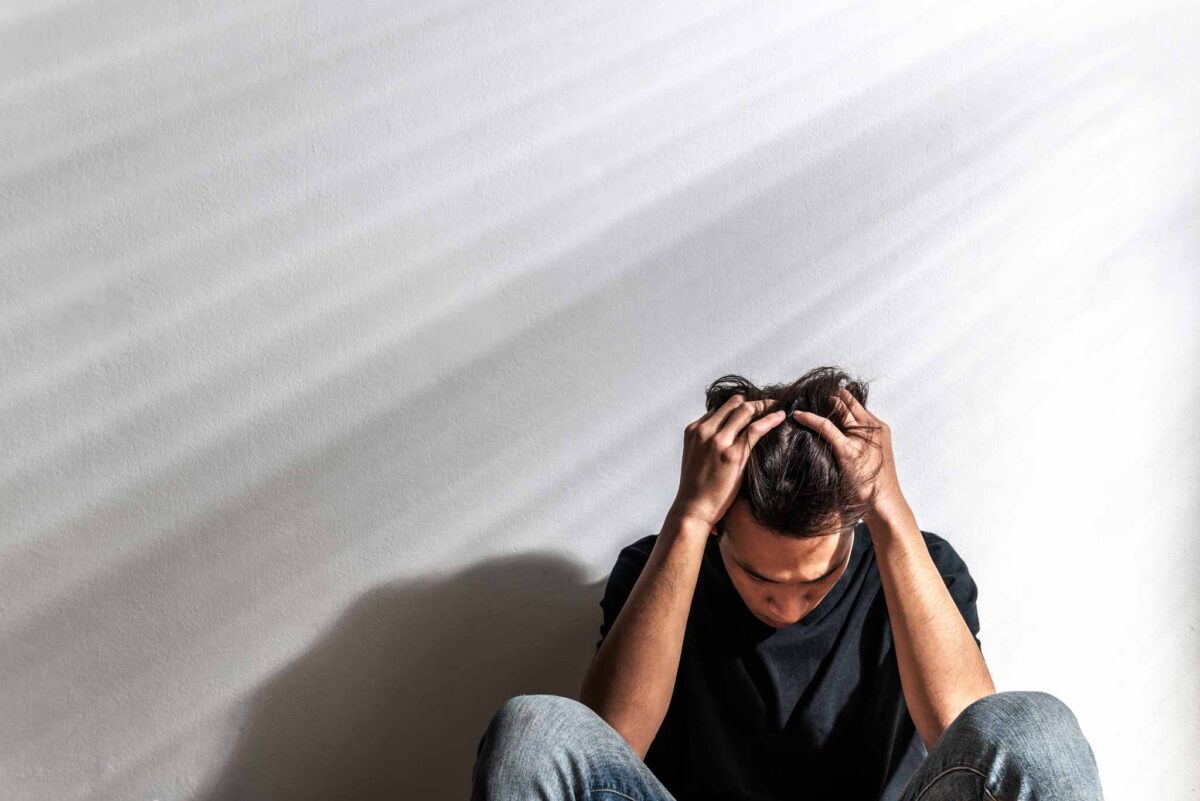 young man with his hands on his head experiencing signs of drug abuse