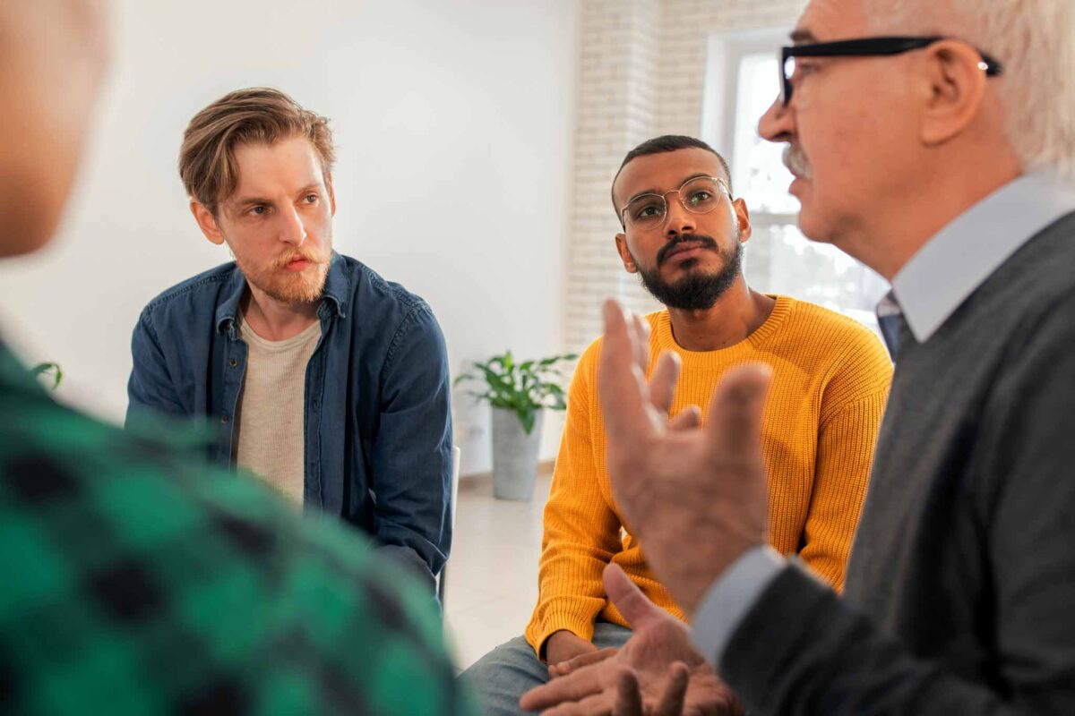 young men in group therapy discussing symptoms and dangers of drug abuse